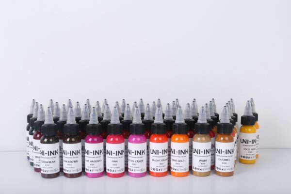 Uni-Ink professional tattoo ink bottles in multiple colours including pink, orange, brown, gold and magenta arranged in a row.